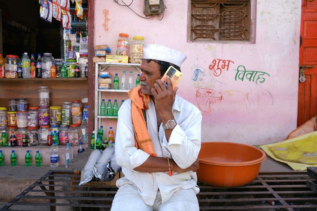 Shop owner taking an order on his phone outside his store